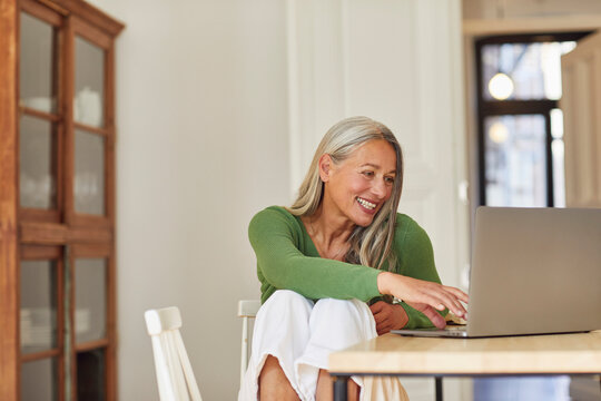Smiling businesswoman using laptop at home