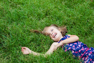 Laughing little girl lying on a meadow in summer