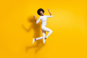 Fototapeta na wymiar Full body photo of attractive young dark skin woman jump up show v-signs isolated on yellow color background