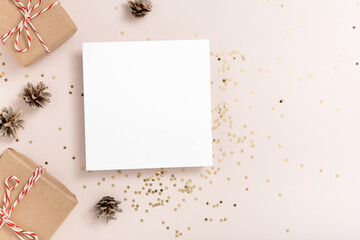 Christmas. Blank square paper mockup, golden stars confetti, bumps, gift boxes on beige background