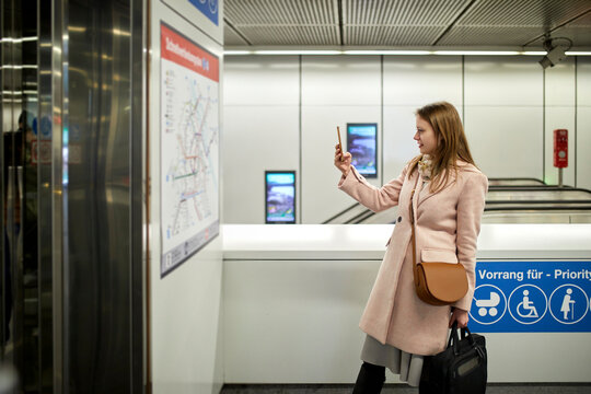 Austria, Vienna, young woman taking photo of map at underground station