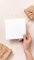 Female hand holds blank square paper mockup Christmas and New Year