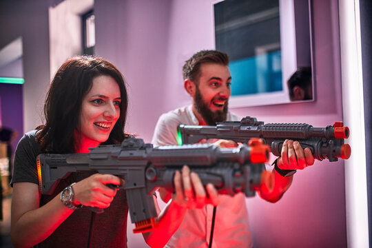 Happy couple playing and shooting with rifles in an amusement arcade
