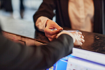 Close-up of woman paying contactless with credit card at reception desk