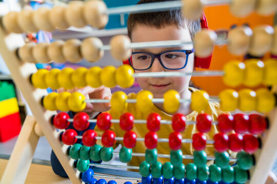 Boy calculating with colorful abacus at home - Powered by Adobe