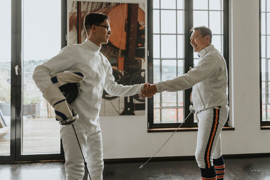 Father and son shaking hands after fencing in loft