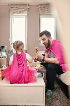 Father and daughter playing superhero and superwoman