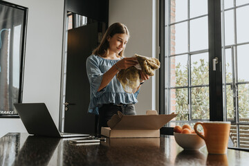 Girl unpacking scarf received through online shopping at home