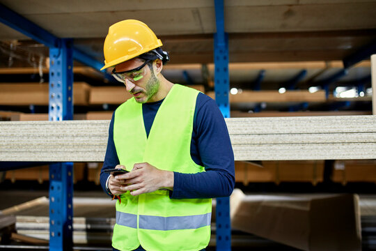 Worker using cell phone in factory warehouse