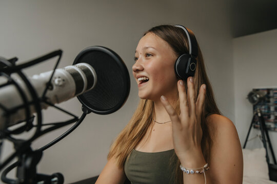 Close-up of happy teenage girl singing against wall in recording studio