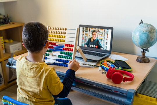 Boy using abacus with teacher on video call during homeschooling
