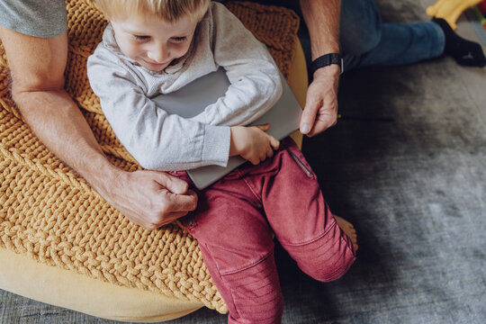 Father struggling while taking digital tablet from displeased boy