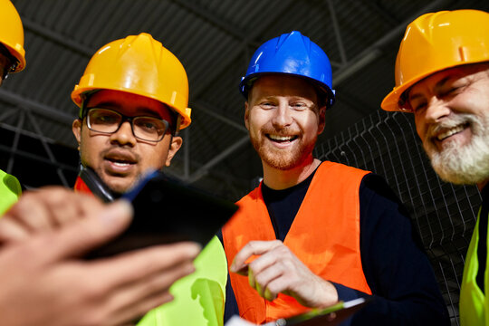 Happy workers in factory warehouse talking and using tablet