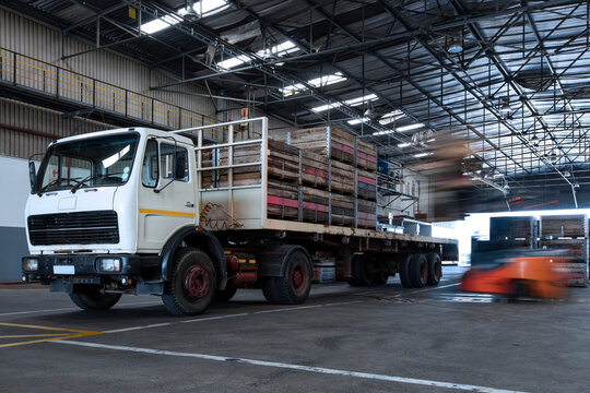 Forklift loading crates on parked truck in warehouse
