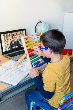 Elementary student using abacus with teacher on video call during homeschooling