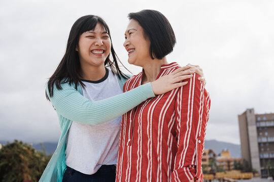 Happy asian mother and daughter having fun hugging outdoor - Focus on senior woman face