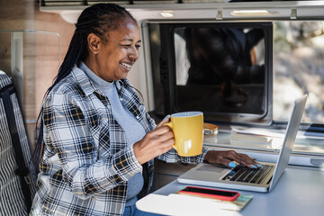 Happy african having fun woman using computer laptop inside mini camper van - Travel and technology...