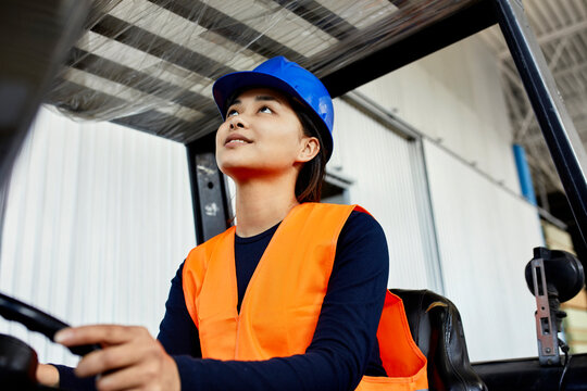Female worker on forklift in factory looking up