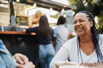Multiracial people eating at food truck restaurant outdoor - Focus on african woman face