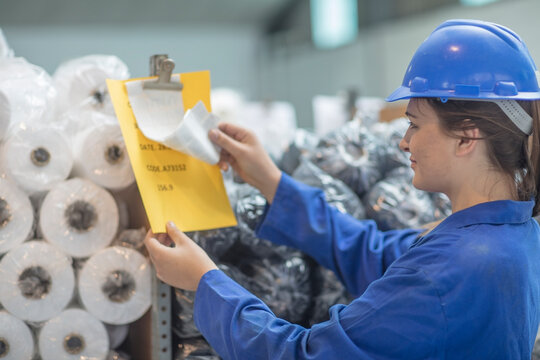Woman wearing hard hat checking document in factory