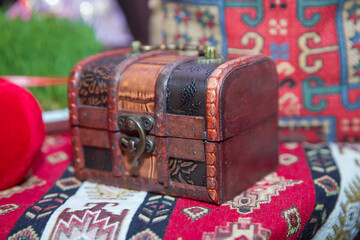 A small wooden box on the carpet . A small wooden box .