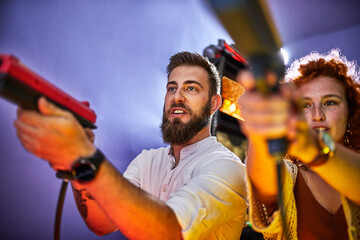 Couple playing and shooting with pistols in an amusement arcade