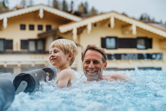 Cheerful son with father enjoying in infinity pool at hotel