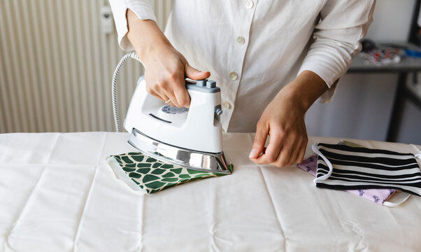 Woman ironing homemade mask on board