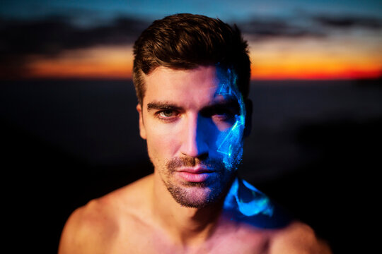 Handsome young man with blue neon color on face