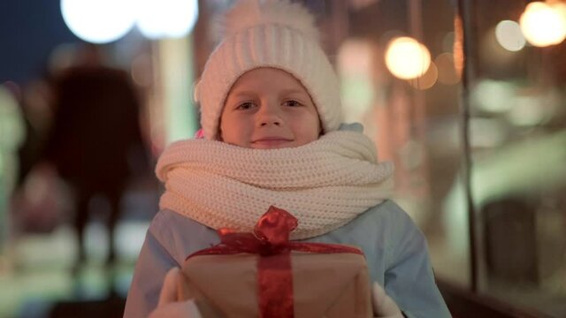Portrait Boy with Gifts box looking and dreaming in Christmas window shopping on traditional Christmas market. Xmas Presents Holidays childhood concept