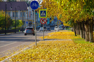 Kolomna, Russia - October, 2021: Zaitsev street on a sunny autumn day. Yellow maple leaves strewn the sidewalk