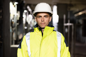 Happy Professional Heavy Industry Engineer Worker Wearing Uniform and Hard Hat in a Steel Factory. Smiling Caucasian Industrial Specialist Standing in a Metal Construction Manufacture