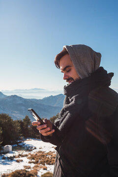 Portrait of a man sending a message with his smartphone in the snow