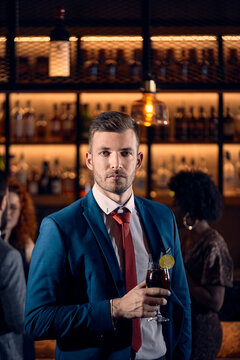 Portrait of a serious young man having a cocktail in a bar