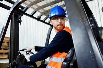 Worker on forklift in factory turning round