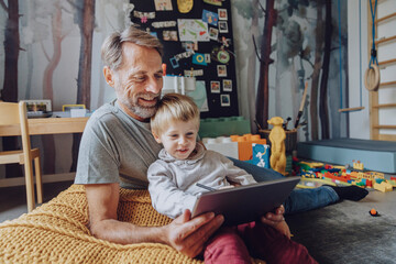 Smiling father with cute son E-learning on digital tablet