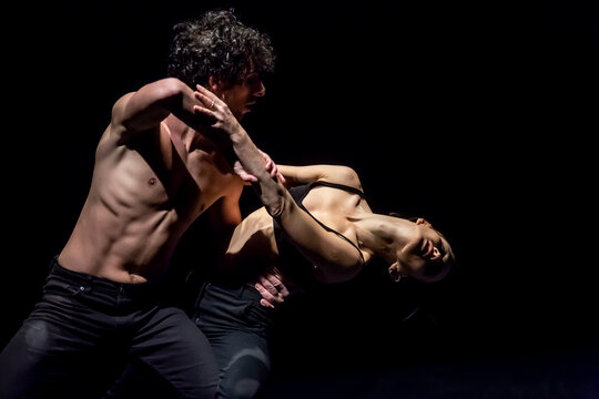 Male and femal dancer performing contemporary ballet on black stage