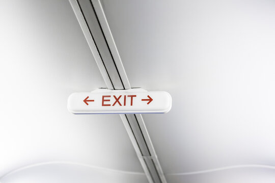Exit sign on white airplane ceiling