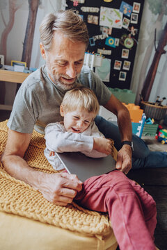 Father struggling while taking digital tablet from displeased son