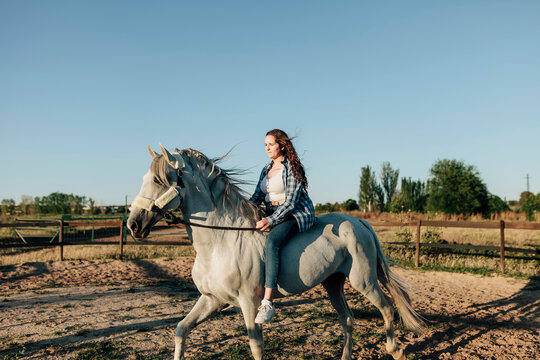 Young woman training with horse at equestrian center against clear sky