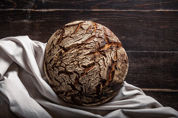 Bun of brown rye bread on table by cloth