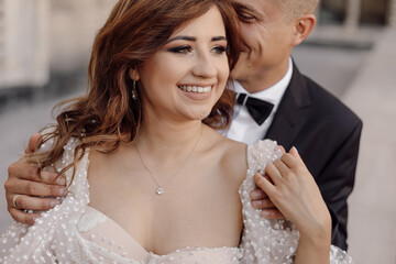 Portrait of the groom and the bride man whispers something in ear to woman she laughs cheerfully in...
