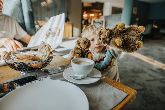 Boy showing Alpine Marmot toy at table in hotel room