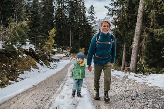 Boy with smiling father hiking in forest at Salzburger Land, Austria
