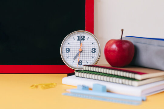 Close-up of alarm clock with school supplies on table