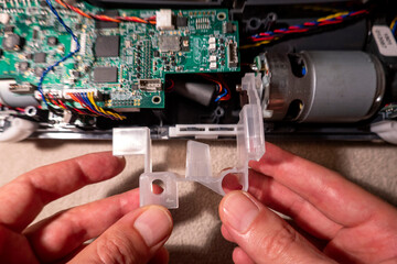 Hands of mature man repairing robotic vacuum cleaner