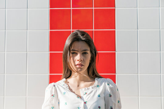 Beautiful young woman against tiled wall during sunny day