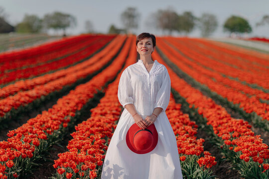 Portrait of smiling woman dressed in white standing in front of tulip field