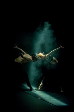 Male and femal dancer performing contemporary ballet on black stage