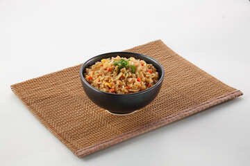 Garlic fried rice with spring onion vegetables in a bowl on bamboo place mat on white background.